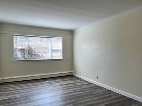 an empty living room with a window and wood floors